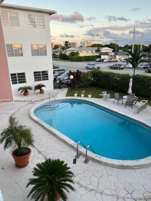 Oval swimming pool with metal ladder and stone-finish paved deck