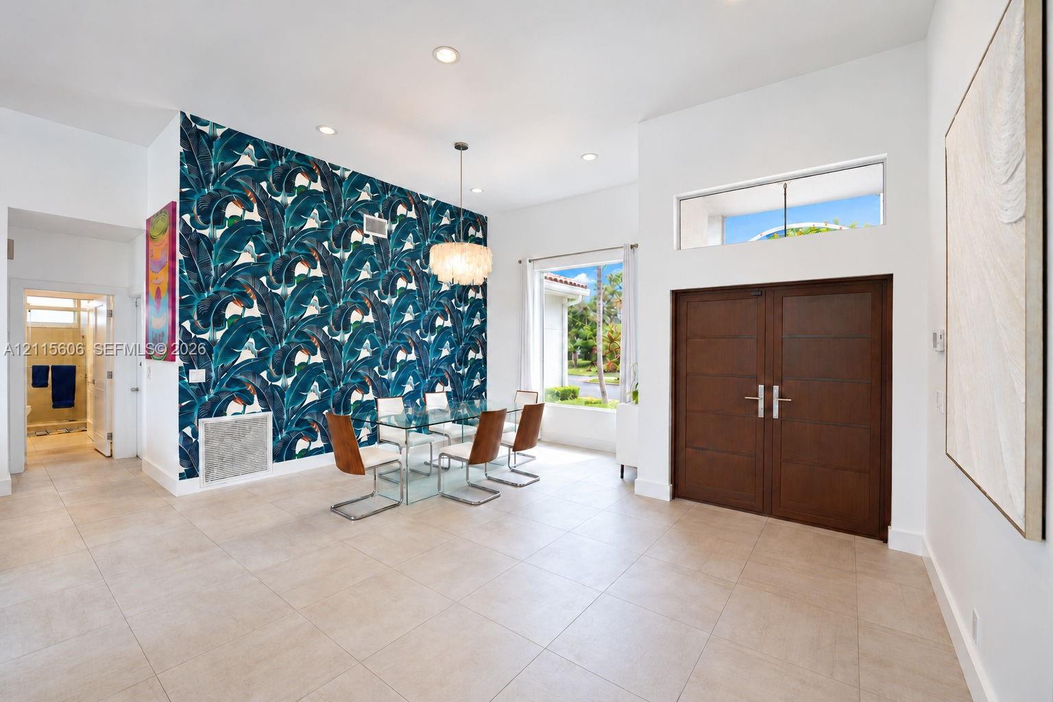 Formal entry featuring double wood doors, transom window, large-format tile flooring, recessed lighting, and a decorative accent wall