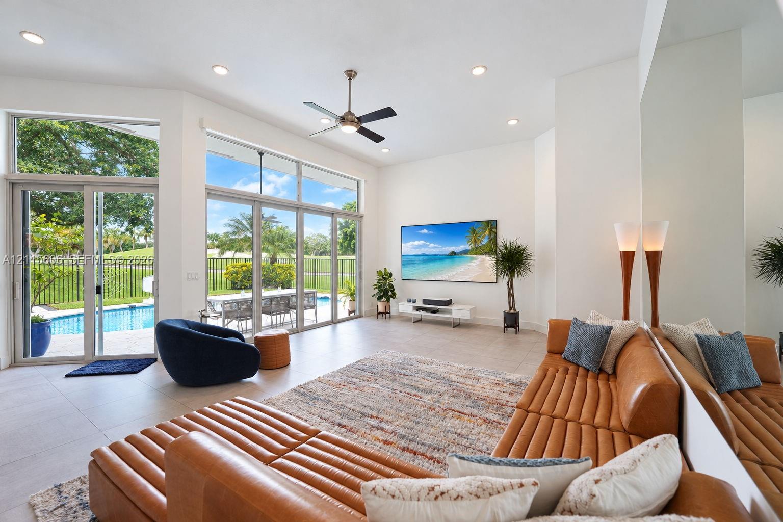 Expansive living area featuring vaulted ceilings, oversized floor-to-ceiling windows, porcelain tile flooring, recessed lighting, and a modern ceiling fan