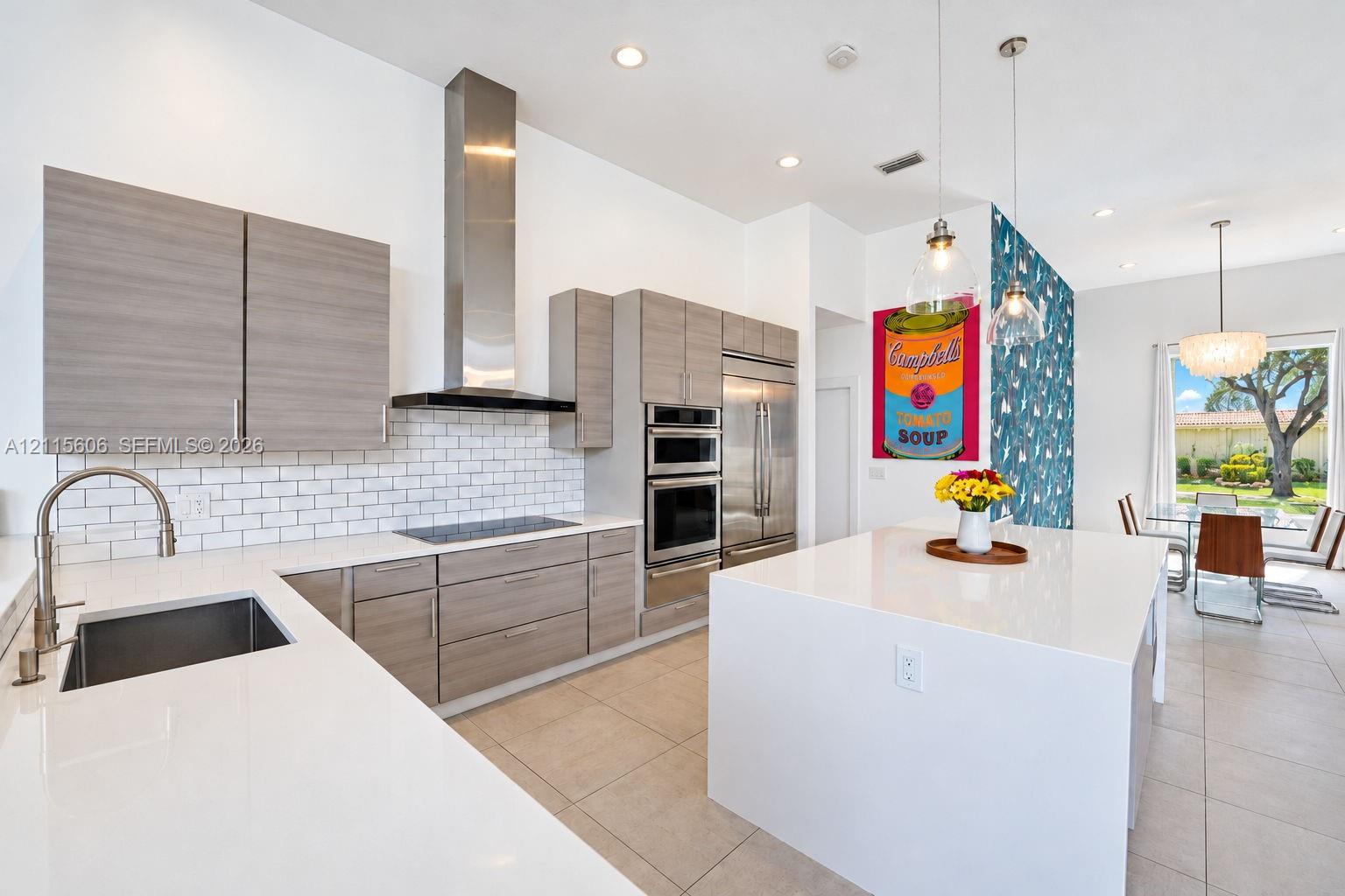 Kitchen featuring flat-panel wood-finish cabinetry, white countertops, a stainless steel chimney-style range hood, subway tile backsplash, and a large center island