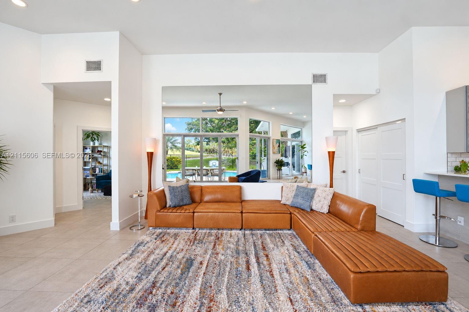 Open-concept interior featuring large-format tile flooring, recessed ceiling lighting, a ceiling fan, and sliding glass doors revealing an outdoor pool