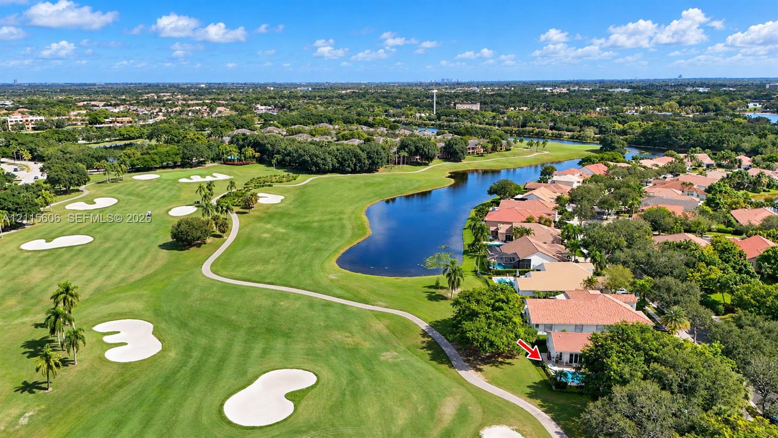 Aerial perspective featuring a property situated on a golf course with a dedicated swimming pool, tile roofing, and surrounding mature landscaping