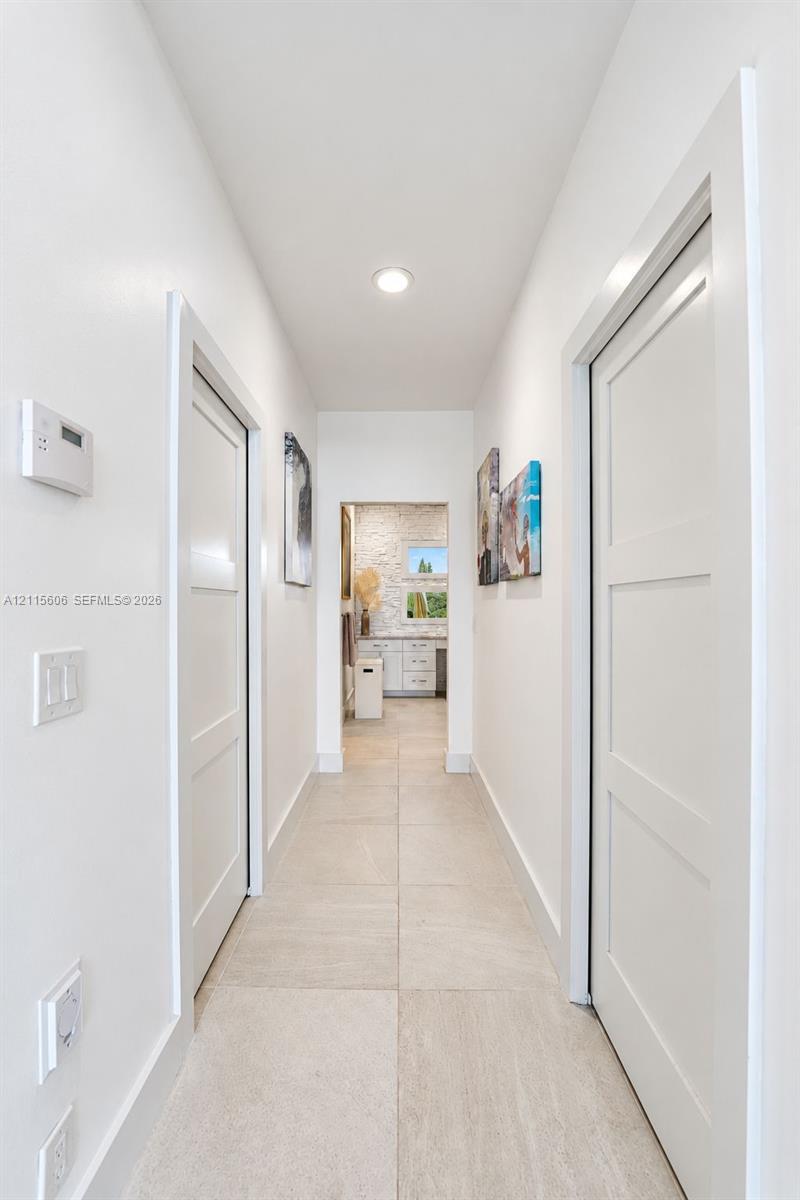 Hallway featuring large-format tile flooring, three-panel interior doors, and recessed lighting
