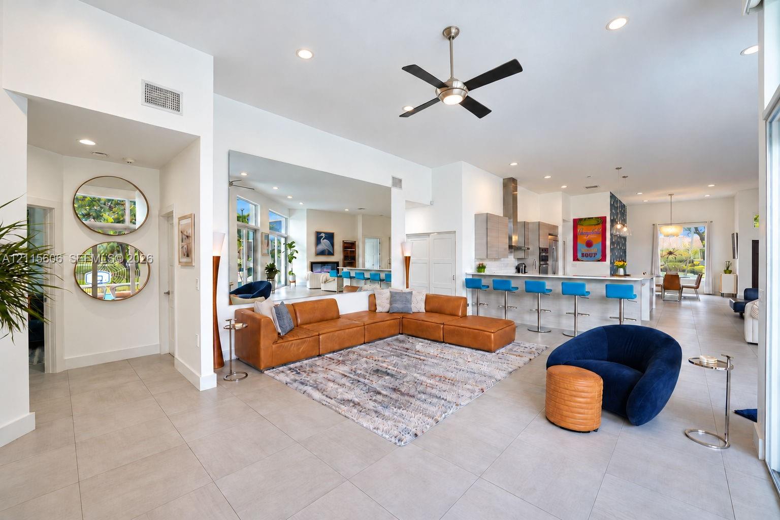 Open-concept interior featuring large-format tile flooring, recessed ceiling lighting, a contemporary ceiling fan, and a kitchen island with integrated seating