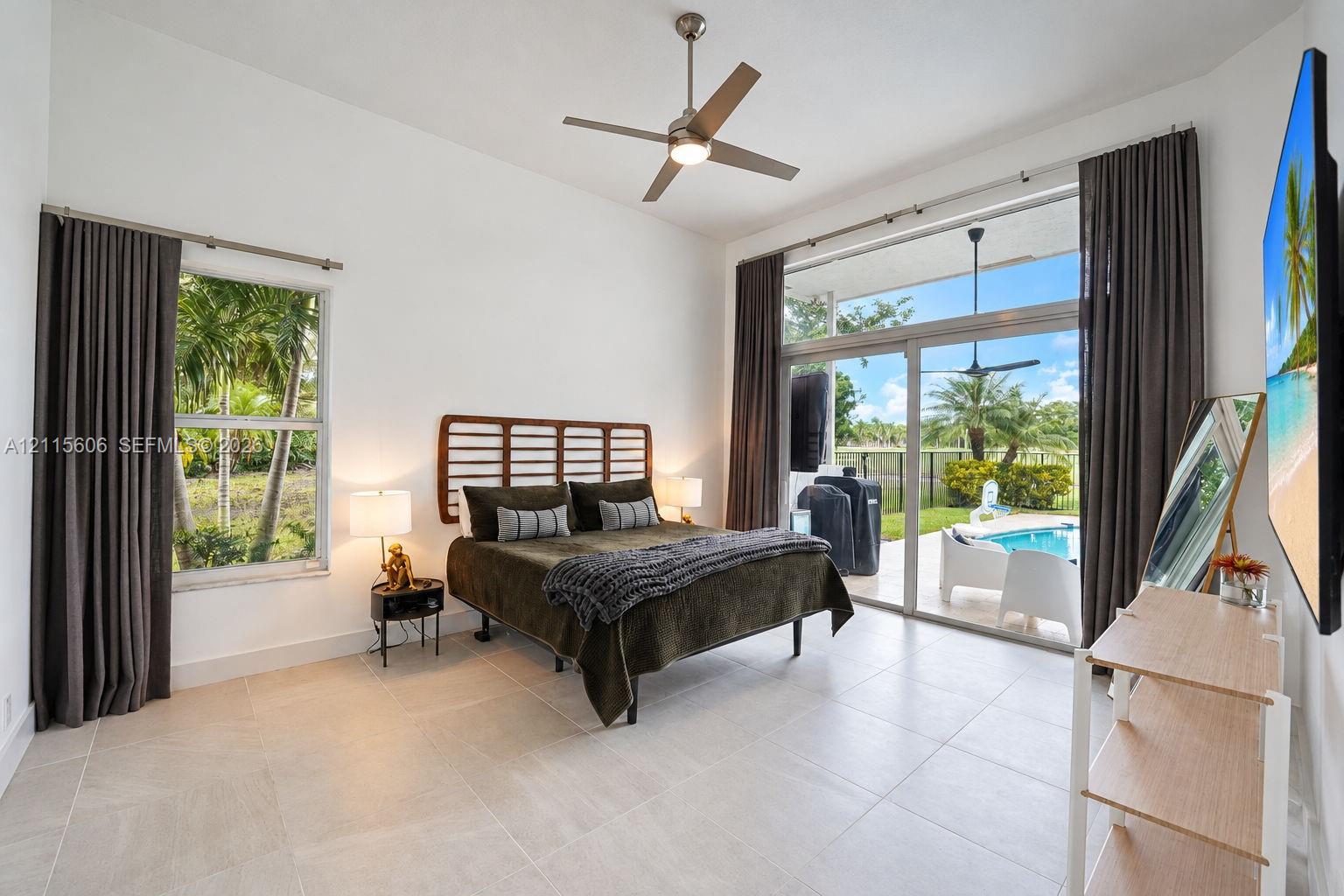 High ceilings featuring a central ceiling fan, large-format tile flooring, oversized windows, and expansive sliding glass doors