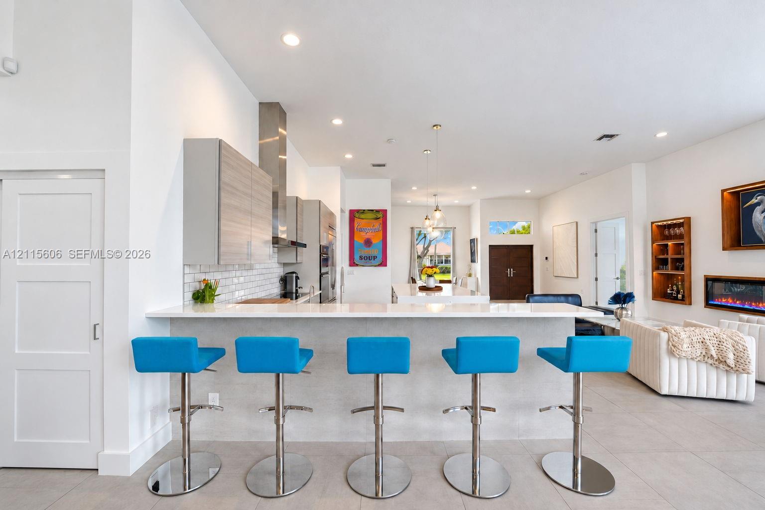 Kitchen featuring quartz countertops, wood-finish cabinetry, stainless steel range hood, built-in wall oven, and tile backsplash