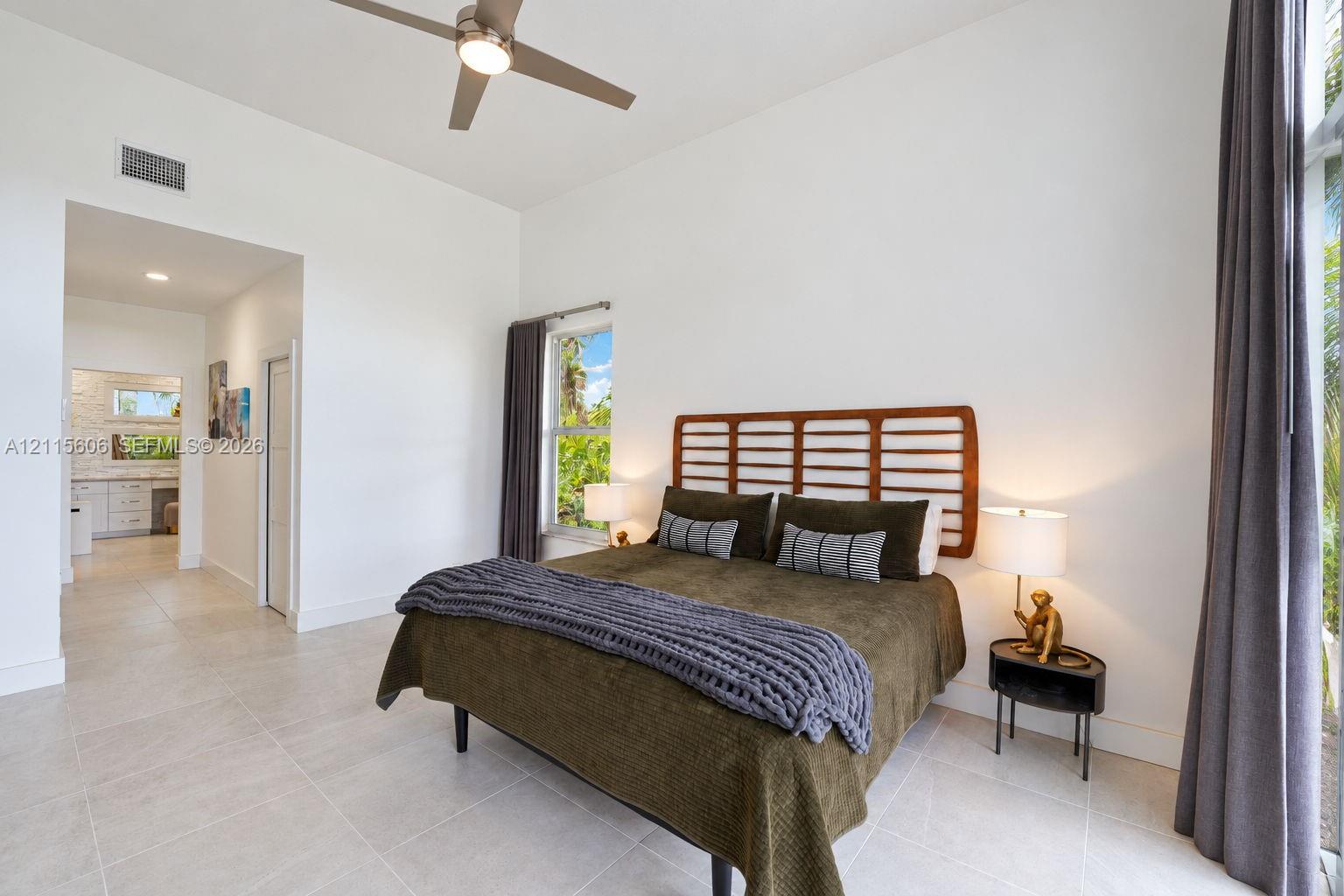 High ceilings, light-tone tile flooring, neutral wall finish, and a ceiling fan with integrated lighting