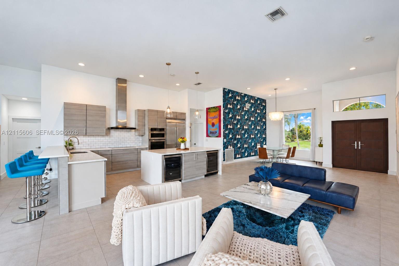 Open-concept living space featuring a gourmet kitchen with horizontal-grain cabinetry, quartz countertops, a stainless steel chimney-style range hood, and large-format tile flooring