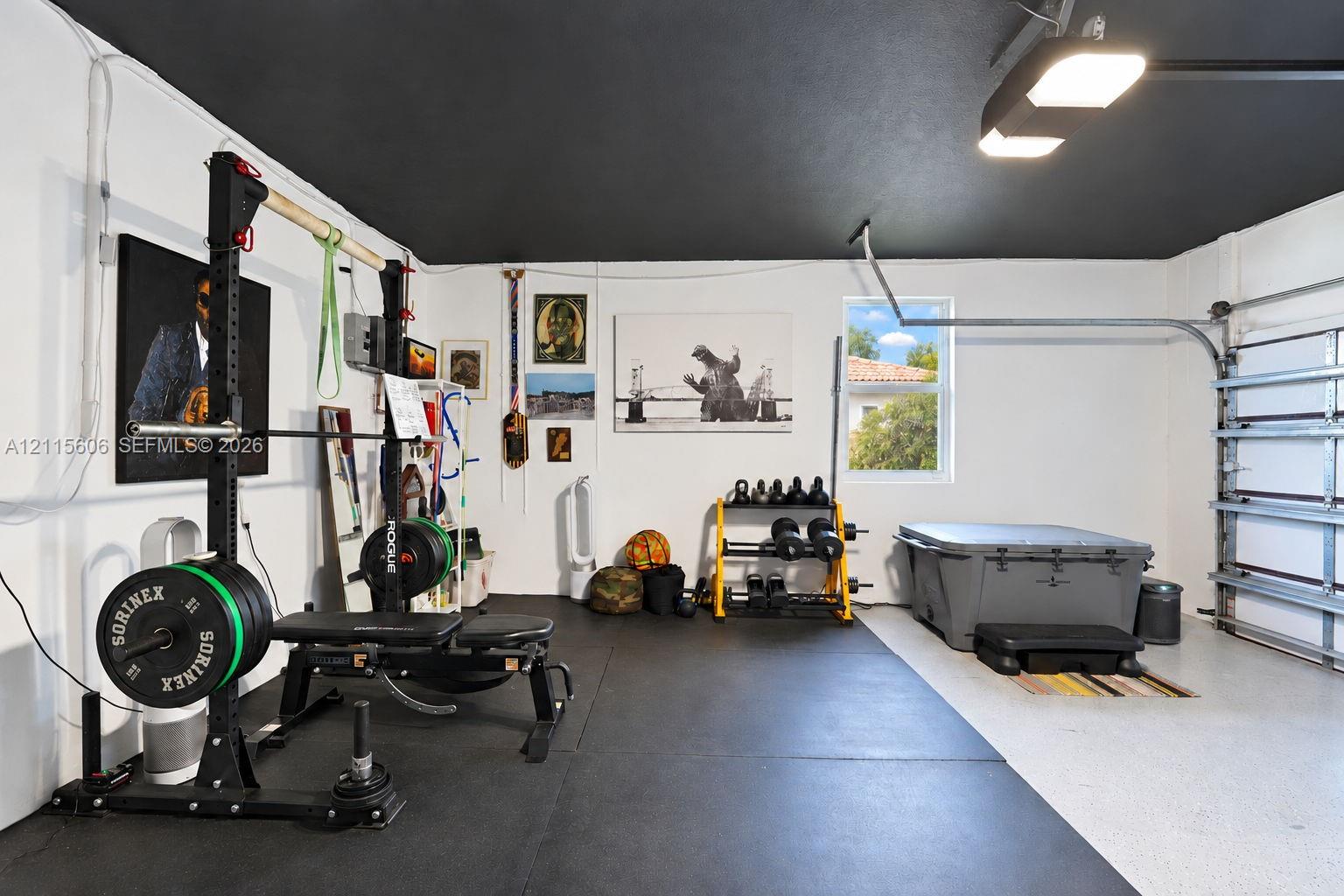 Garage space featuring high-contrast black ceiling paint, epoxy-coated flooring, and overhead LED lighting