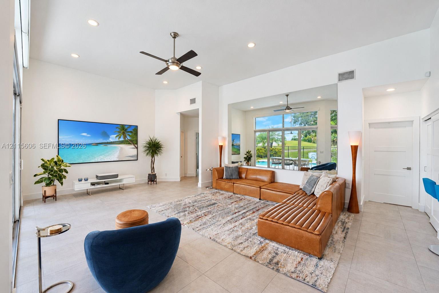 Living area featuring high ceilings, large-format tile flooring, recessed lighting, ceiling fan, and expansive sliding glass doors