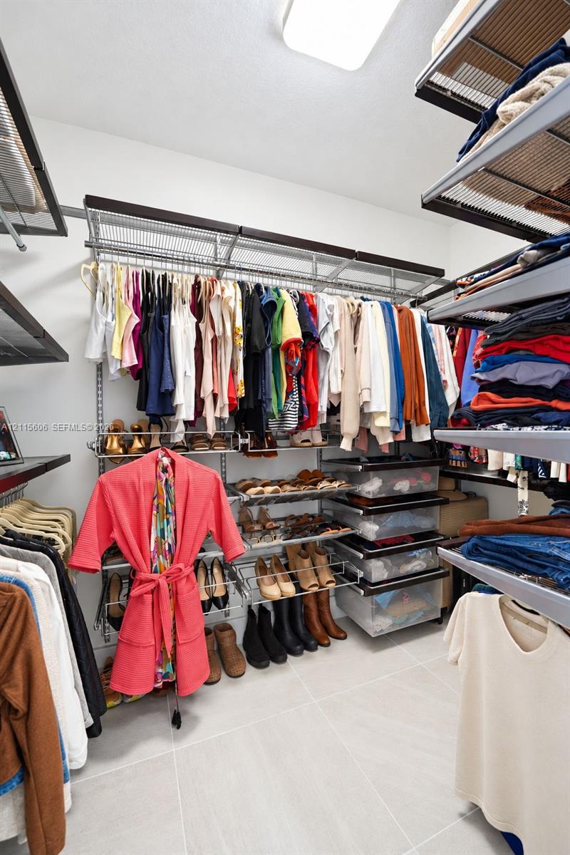Walk-in closet featuring multi-tiered wire shelving, integrated hanging rods, built-in shoe racks, pull-out storage drawers, and tile flooring