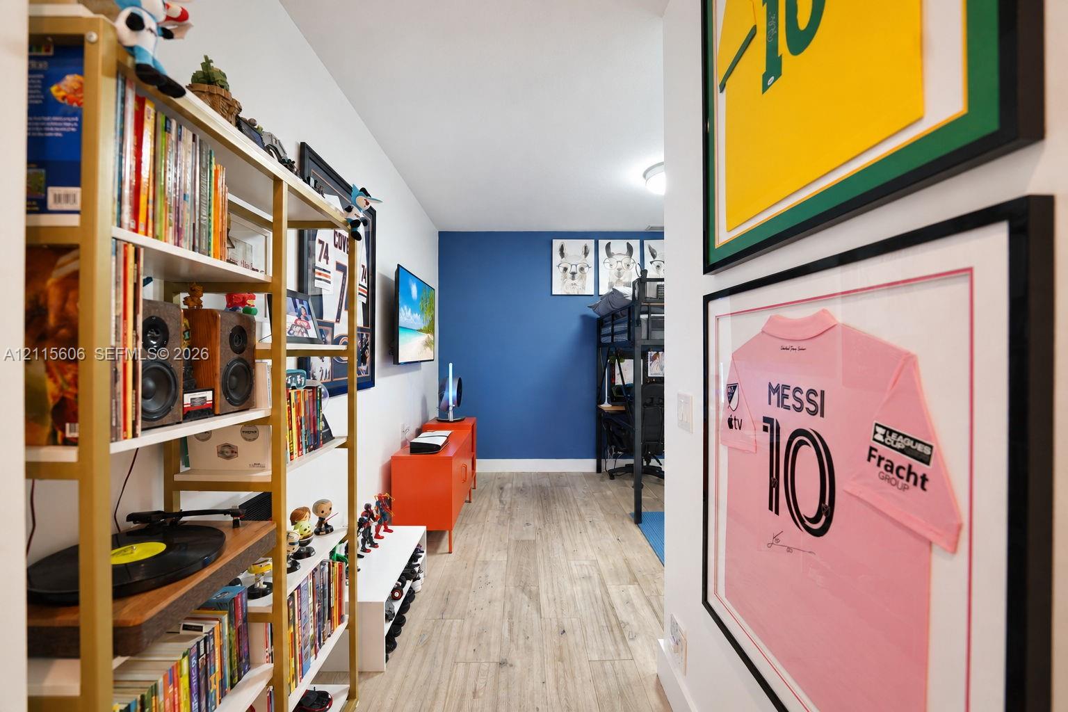 Room interior featuring wood-finish flooring, a bold blue accent wall, and a flush-mount ceiling light fixture
