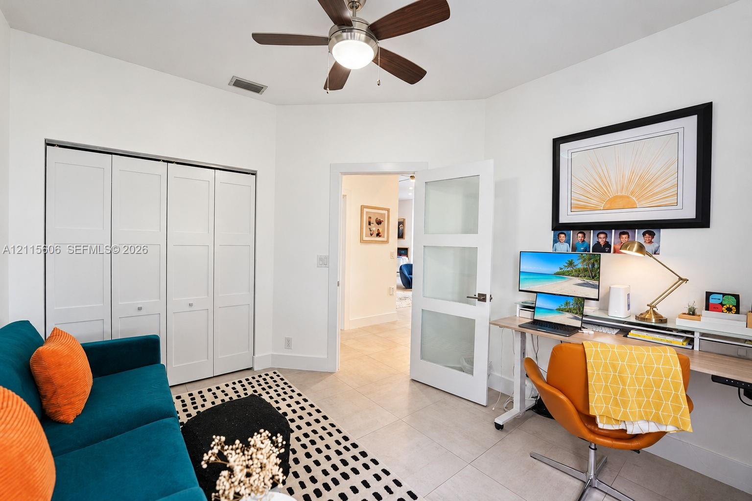 Interior room featuring neutral tile flooring, a multi-panel closet with white doors, a ceiling fan with integrated lighting, and a white interior door with three frosted glass panels