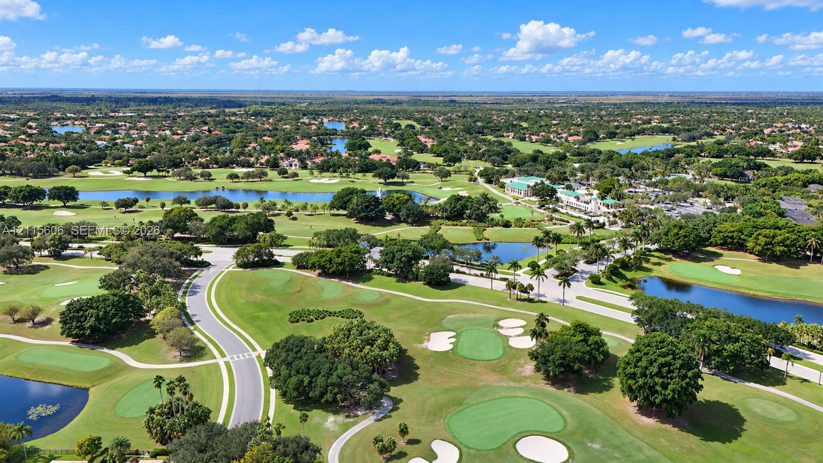 Aerial perspective featuring a golf course, multiple water features, mature trees, and paved thoroughfares