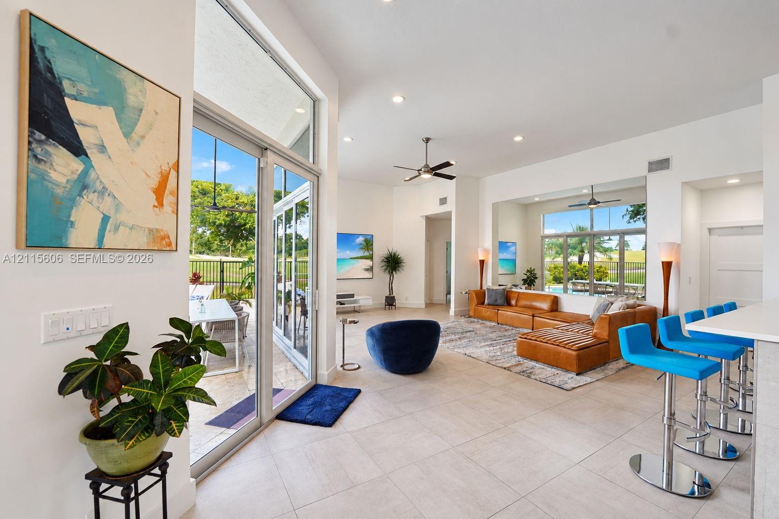 Open-concept interior featuring large-format tile flooring, recessed ceiling lighting, high ceilings, and floor-to-ceiling glass sliding doors