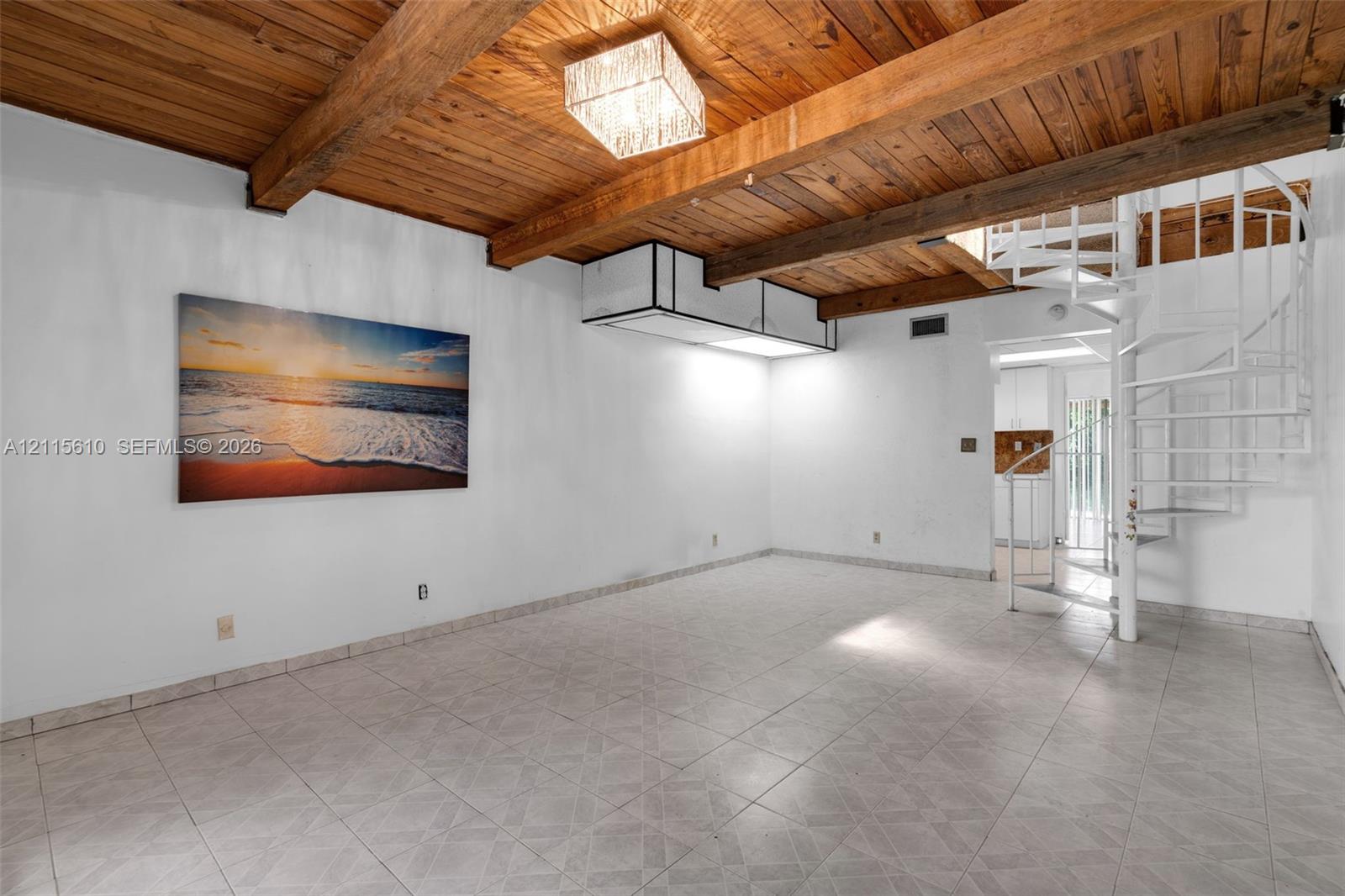 Exposed wood-beam ceiling featuring natural finish planks, white spiral staircase, tile flooring, and integrated rectangular flush-mount lighting