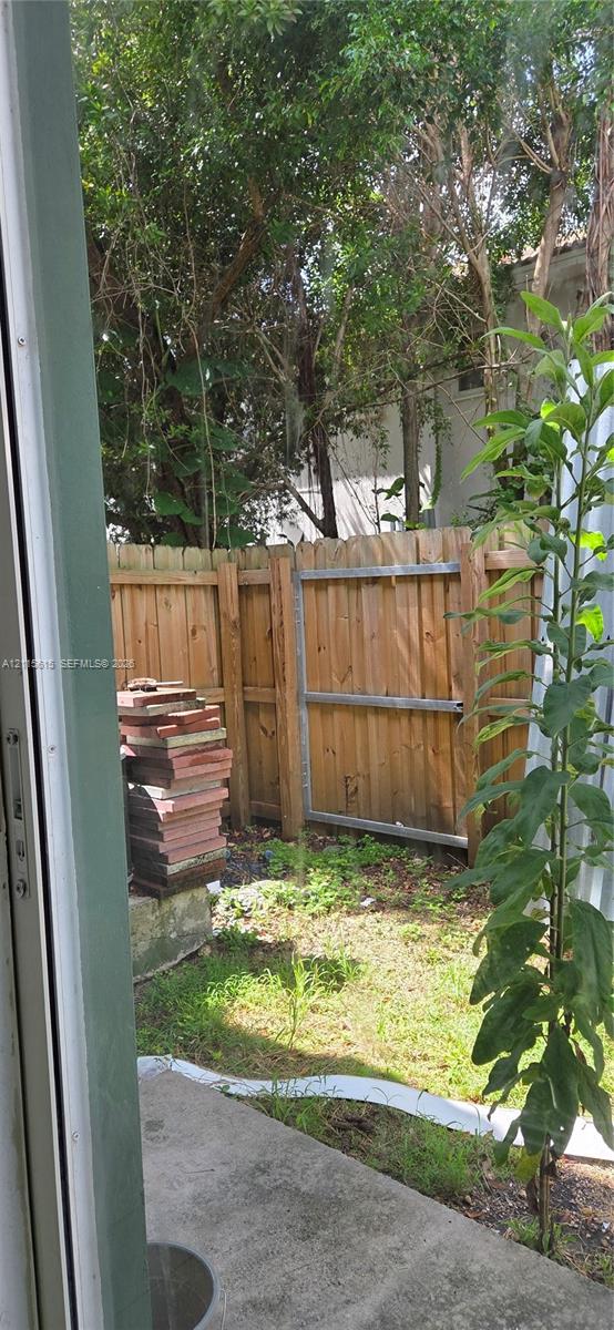 Concrete patio featuring a vertical wood privacy fence and mature trees