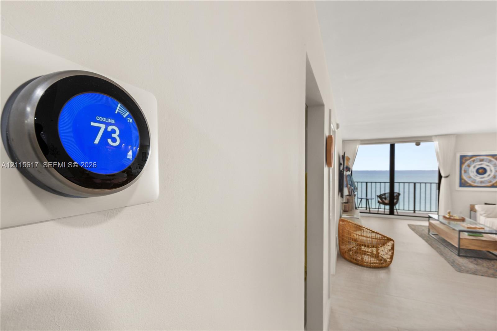 Smart thermostat with digital display, floor-to-ceiling windows, and private balcony with metal railing