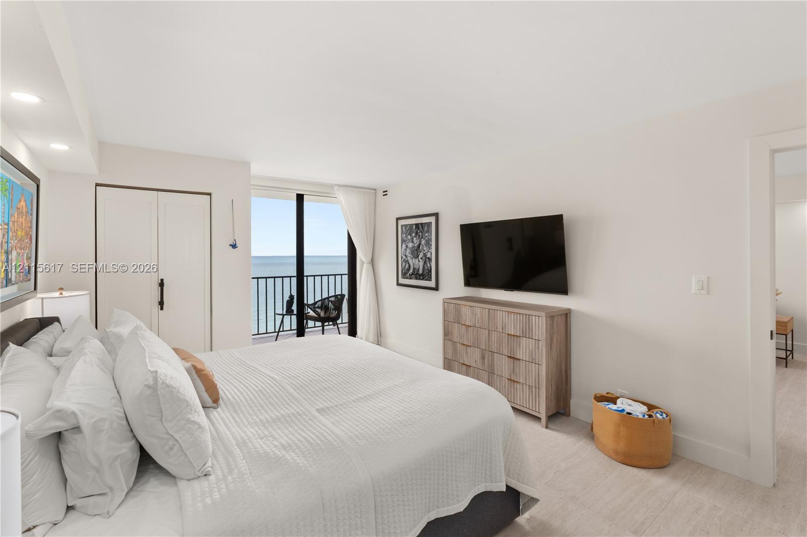 Bedroom featuring light wood-finish flooring, floor-to-ceiling glass door, metal balcony railing, and built-in closet cabinetry