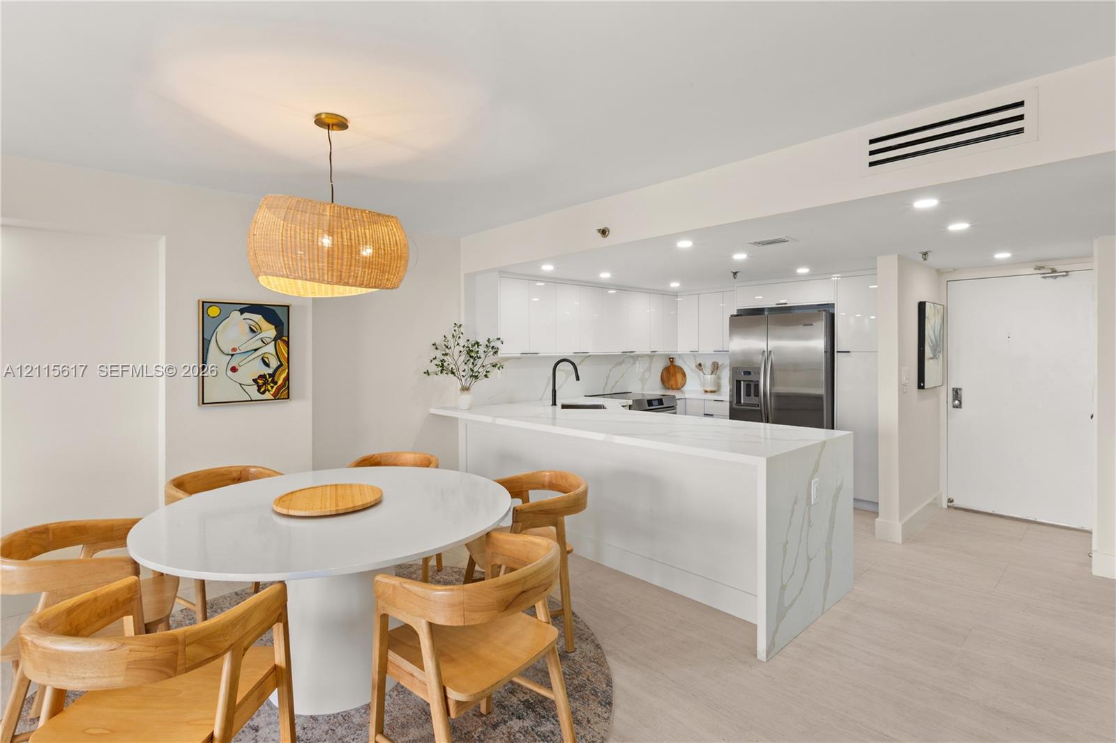 Kitchen featuring a waterfall-edge stone countertop, high-gloss flat-panel cabinetry, stainless steel refrigerator, and recessed lighting, accented by a woven drum pendant light