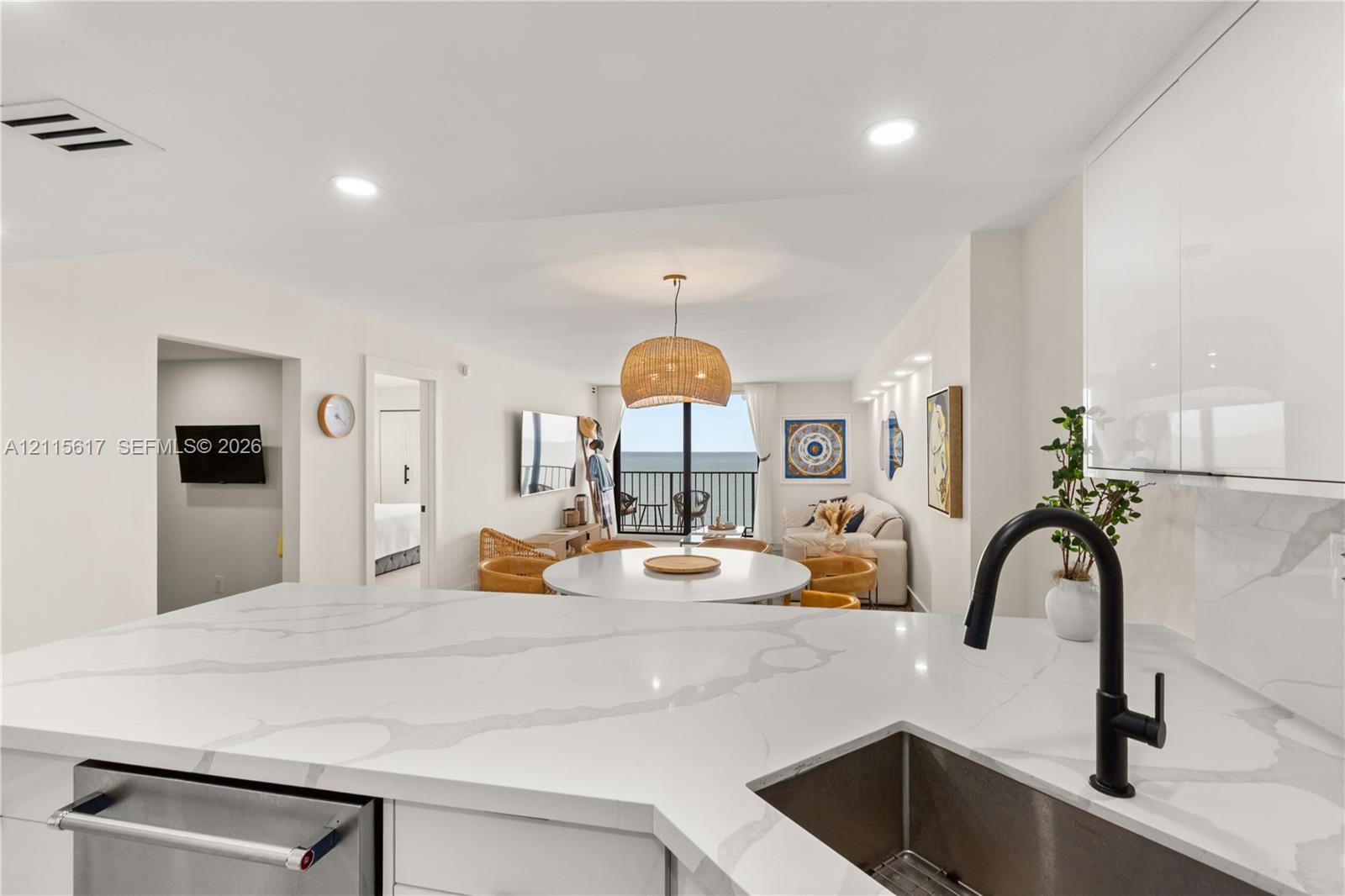 Kitchen featuring white cabinetry, stone-patterned countertops, a stainless steel undermount sink, and a matte black gooseneck faucet