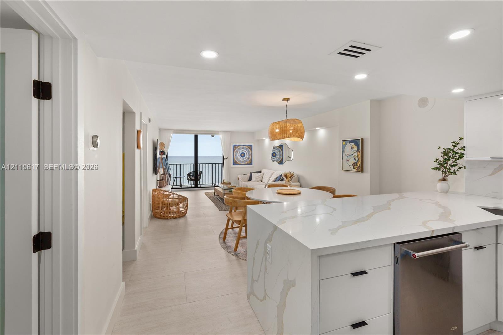 Kitchen featuring a stone-surface waterfall island, flat-panel cabinetry, stainless steel dishwasher, tile flooring, and recessed lighting