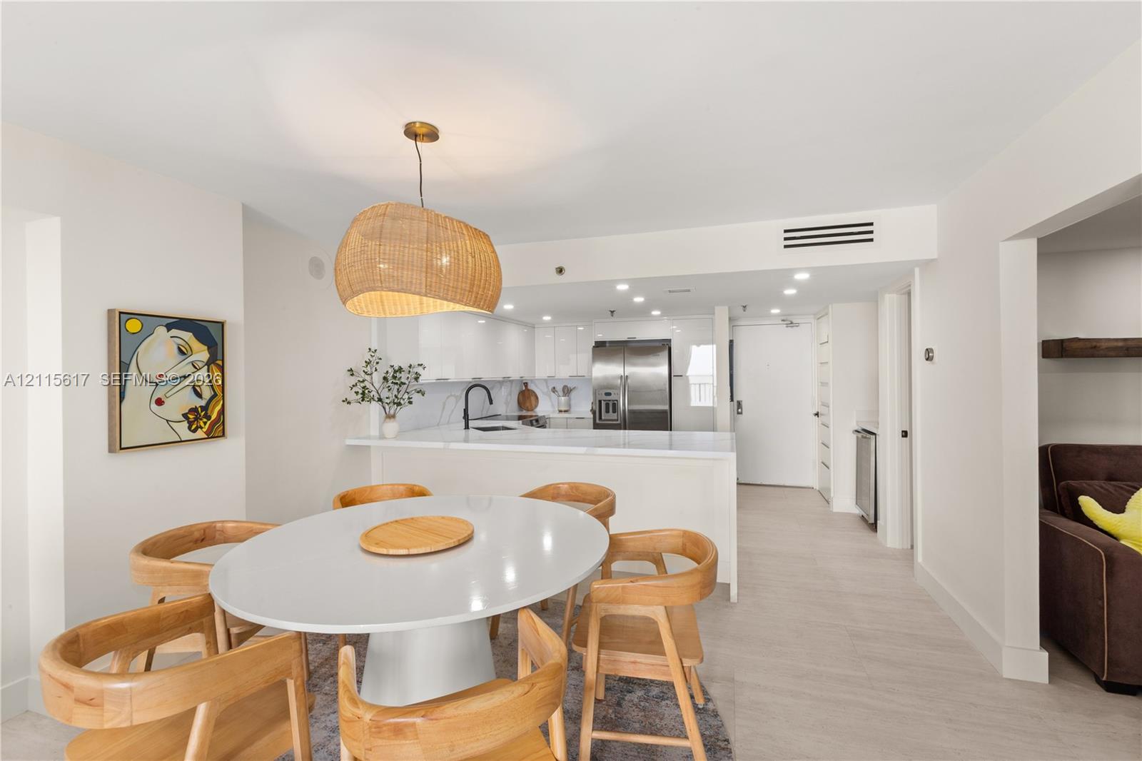 Kitchen featuring high-gloss cabinetry, stone-finish countertops, stainless steel appliances, and a black gooseneck faucet, complemented by light-toned wood-finish flooring
