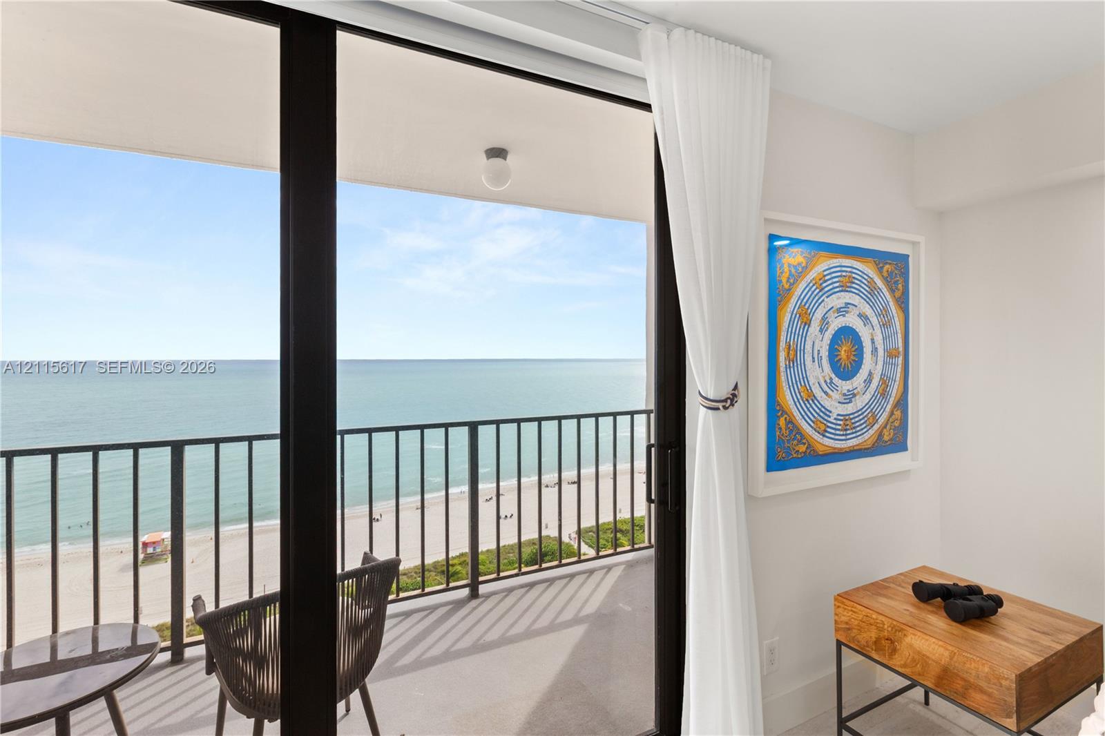 Private balcony featuring a metal railing and oceanfront exposure, accessed via expansive floor-to-ceiling sliding glass doors
