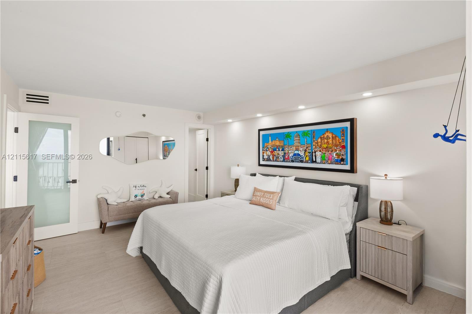 Neutral-toned room featuring recessed ceiling lighting, light wood-finish flooring, and a frosted glass door