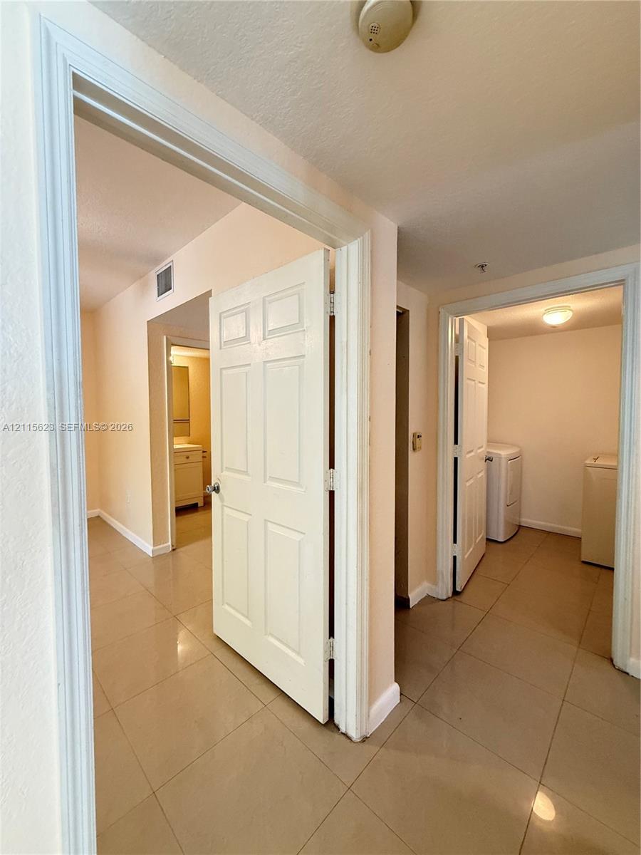 Interior hallway featuring neutral-toned tile flooring and six-panel interior doors