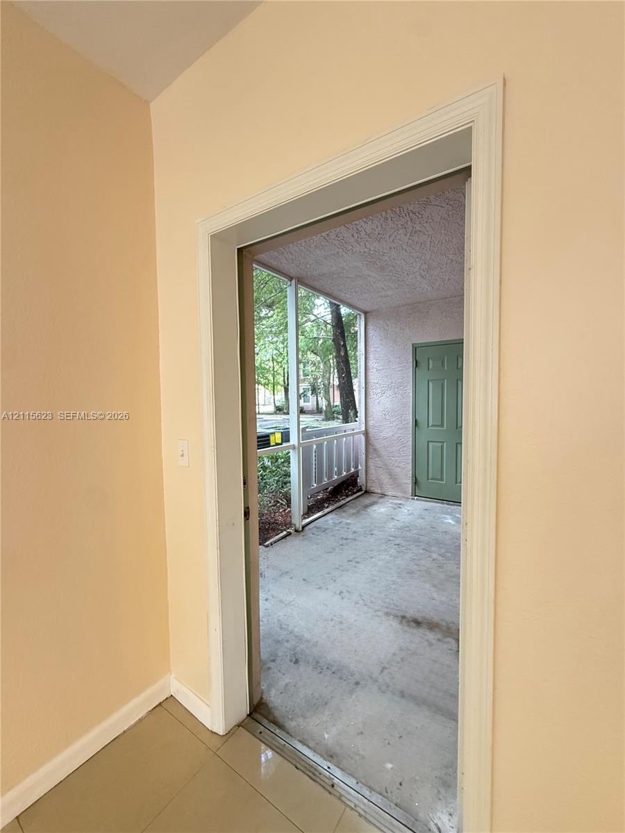 Screened-in porch featuring a concrete floor and a solid-core six-panel door