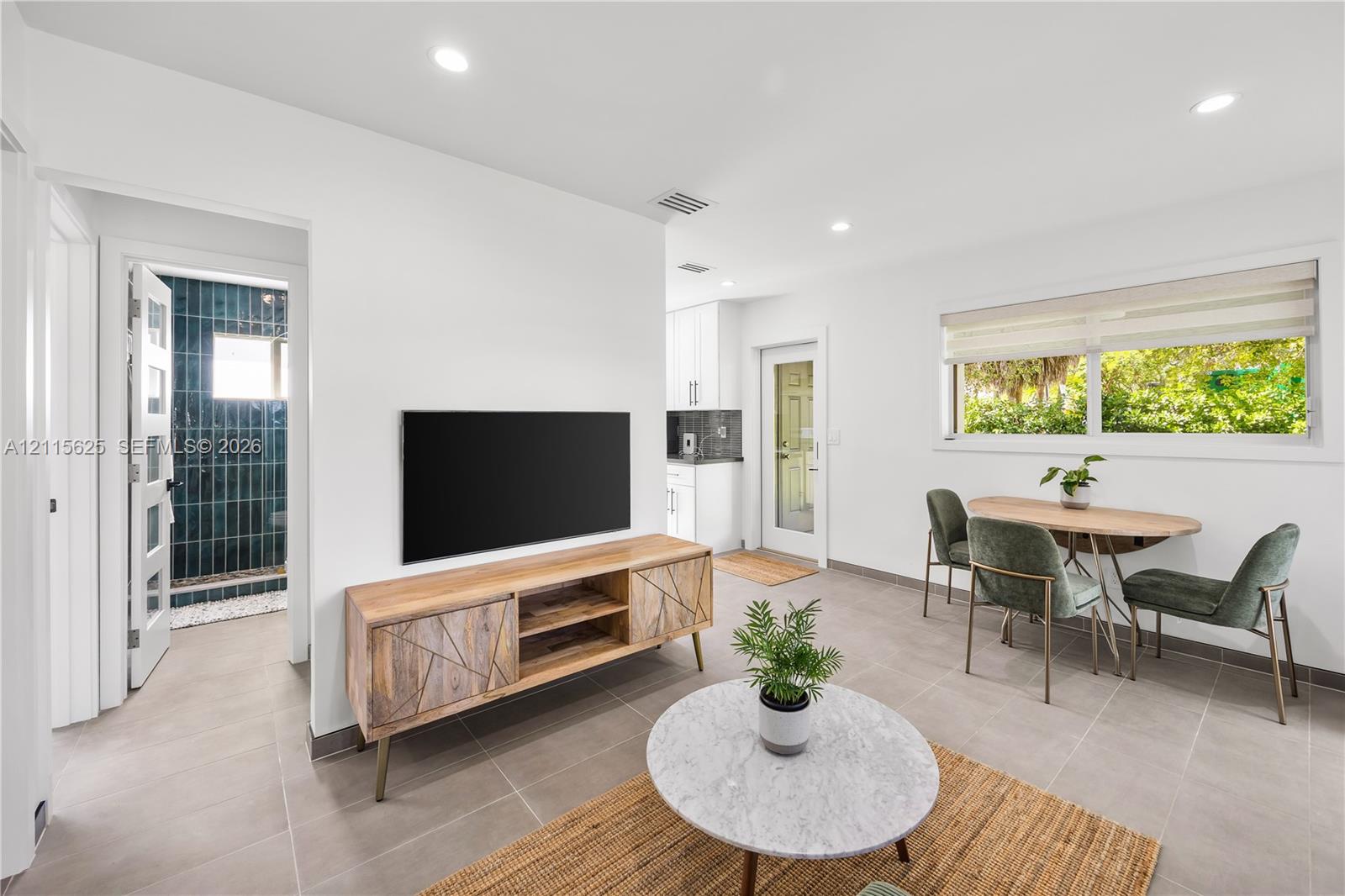 Neutral ceramic tile flooring, recessed ceiling lighting, horizontal window blinds, and a glass-panel exterior door