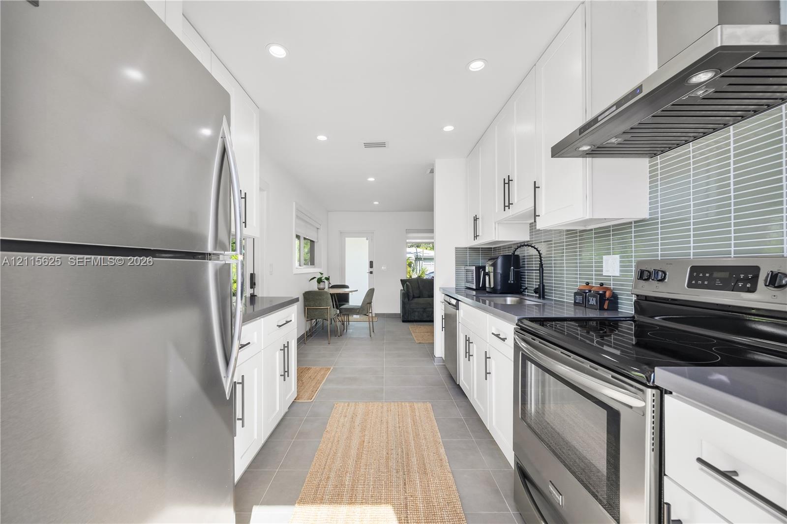 Kitchen featuring white cabinetry, gray countertops, stainless steel appliances, a glass-tiled backsplash, and recessed lighting