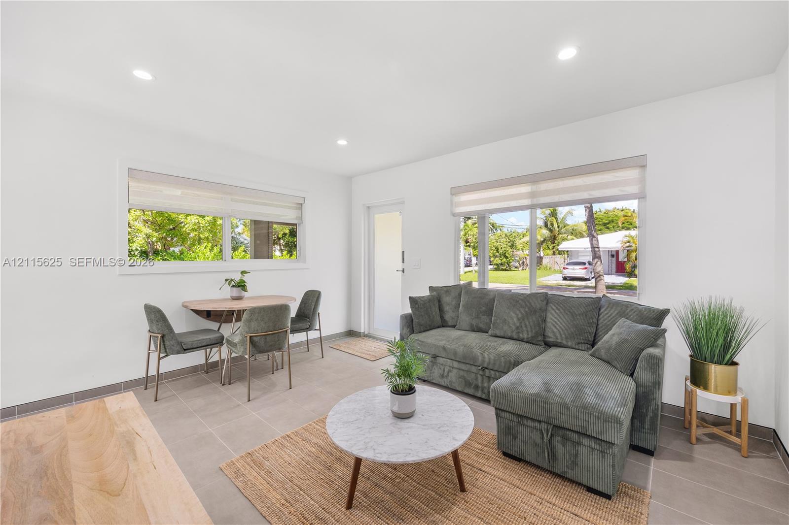 Bright interior featuring neutral wall tones, ceramic tile flooring, recessed ceiling lighting, and large windows with integrated roller shades