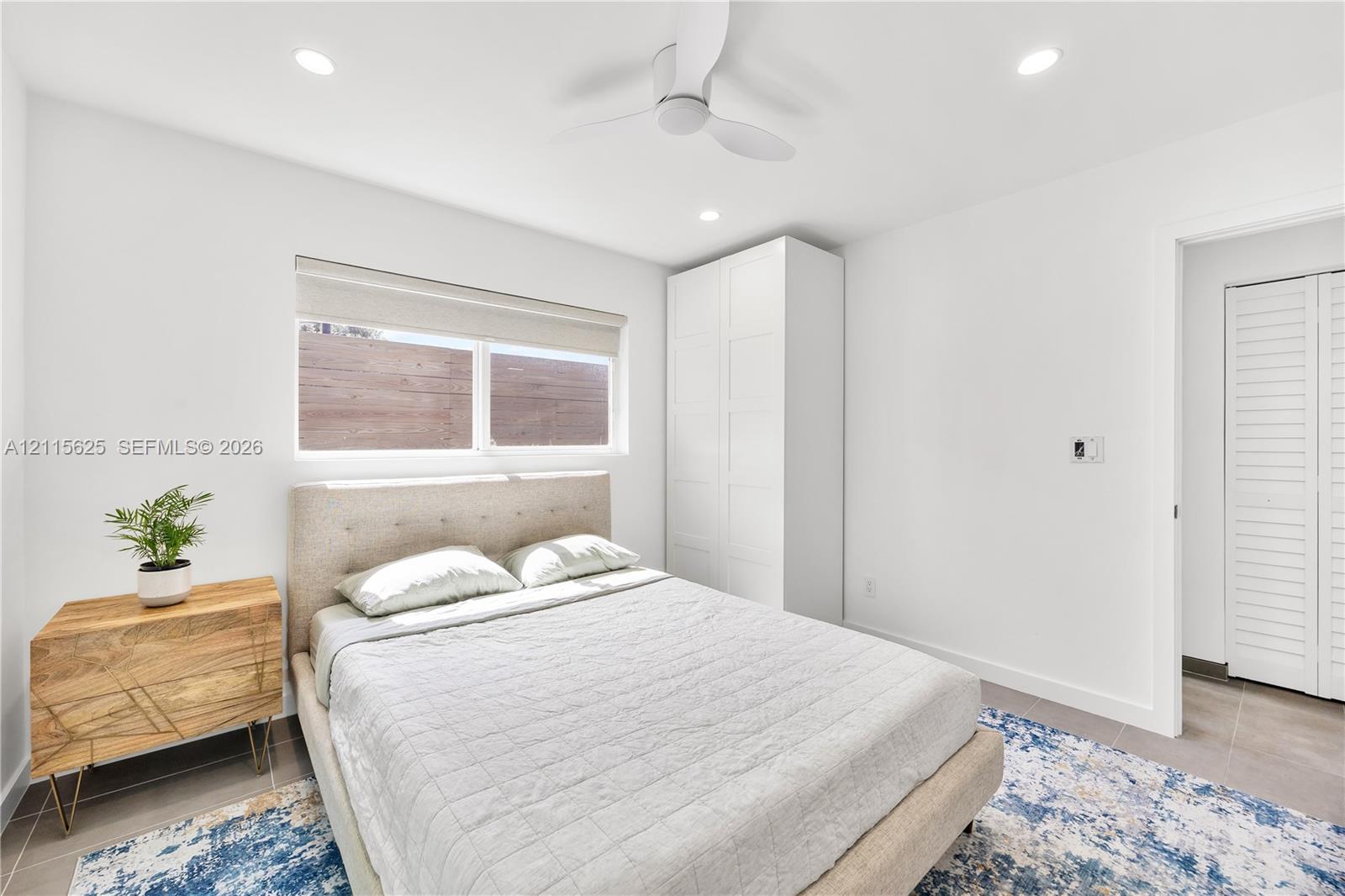 Room featuring recessed lighting, a white ceiling fan, a horizontal window, built-in floor-to-ceiling cabinetry, and a closet with louvered doors