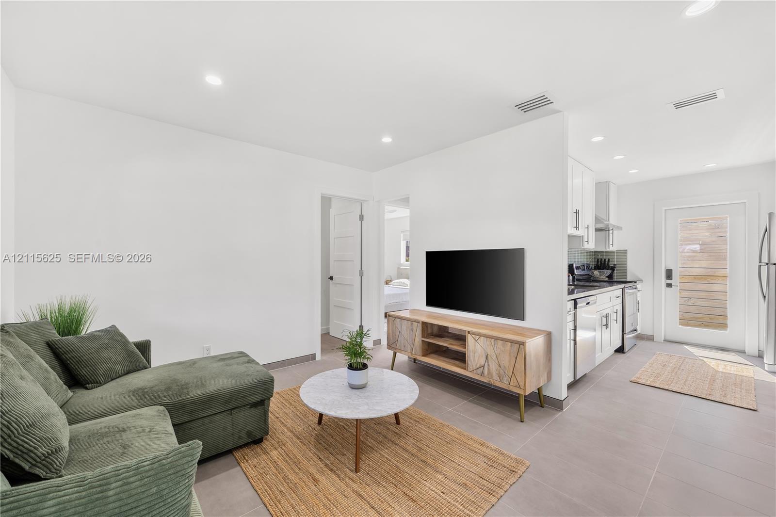 Open-concept interior featuring large-format tile flooring, recessed lighting, and white cabinetry