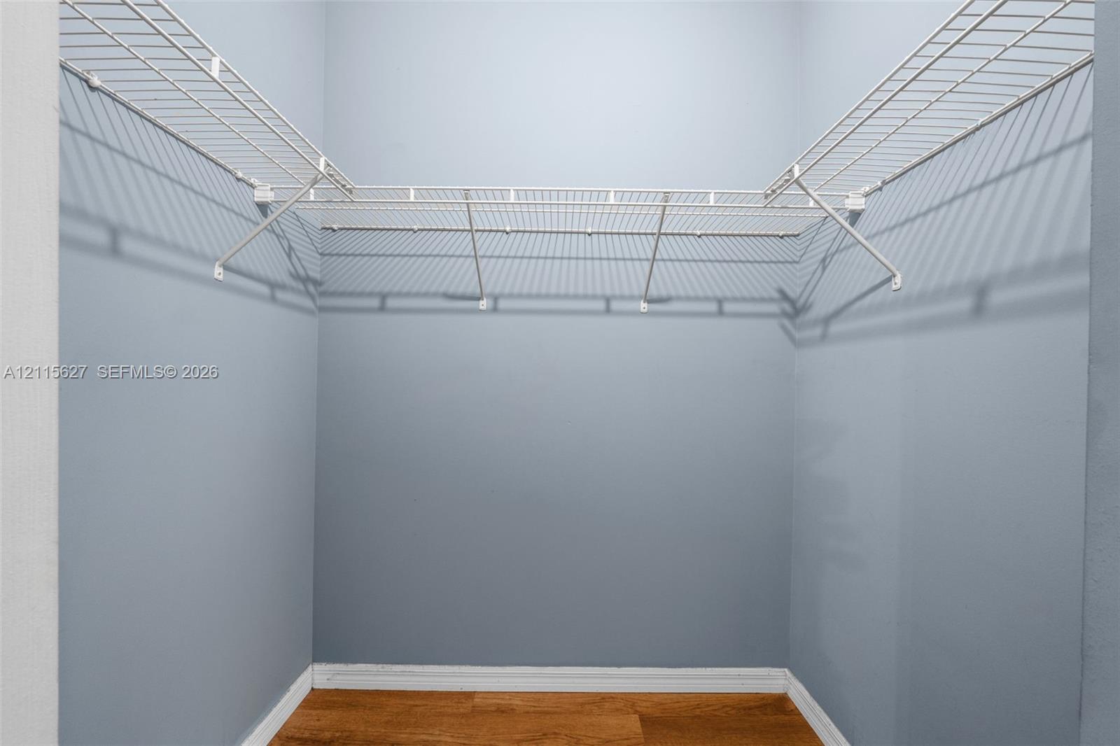 Walk-in closet featuring white wire shelving and wood-finish flooring