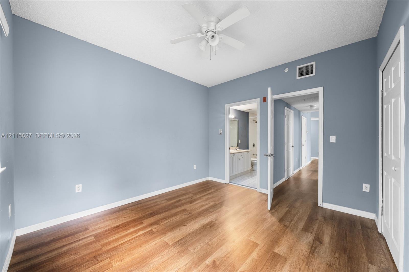 Room featuring wood-finish flooring, a white ceiling fan with integrated lighting, and painted walls