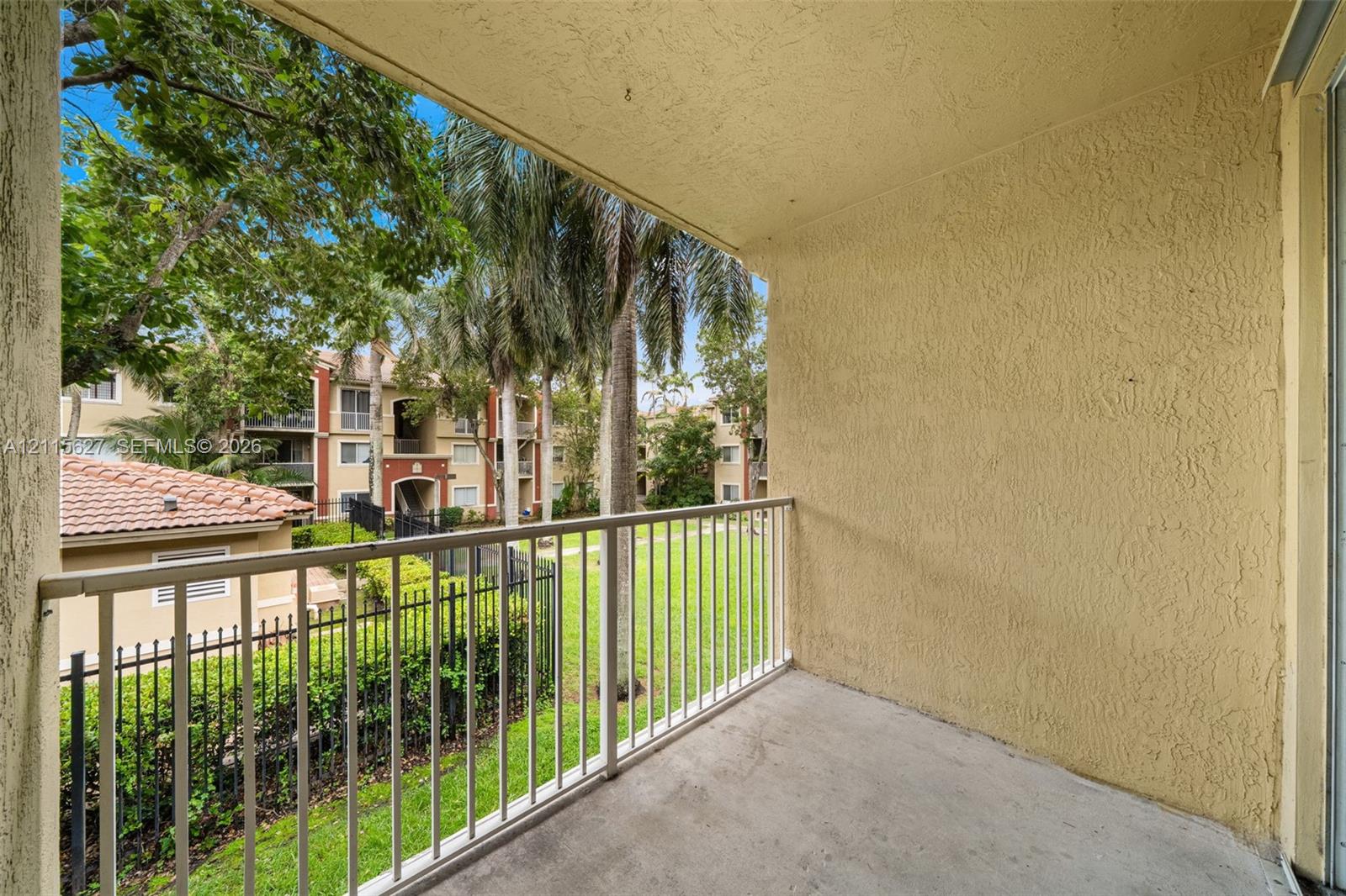 Covered balcony featuring a concrete floor, stucco walls, and metal railing