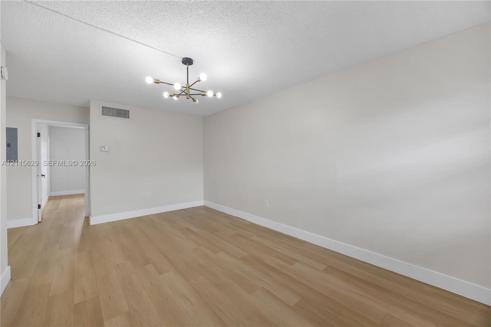 Spacious interior featuring wood-finish flooring, neutral wall paint, and a modern multi-arm light fixture