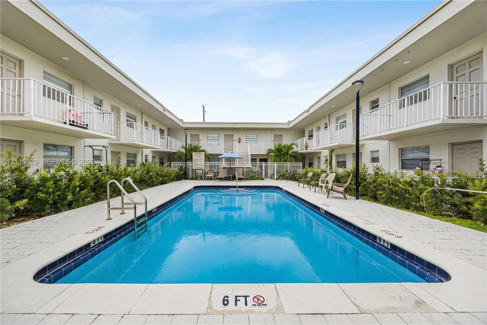 In-ground swimming pool with tile surround, white metal railings, and perimeter landscaping