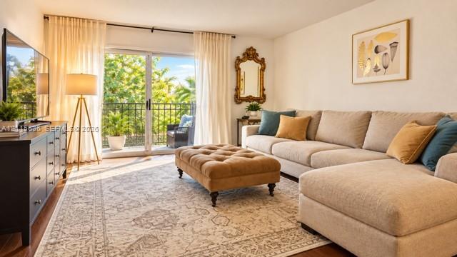 Living area featuring sliding glass doors, a wrought-iron balcony railing, and wood-finish flooring