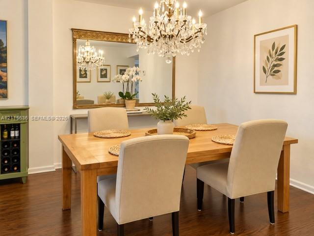 Formal dining area featuring wood-finish flooring, a crystal chandelier, and a large wall-mounted mirror with an ornate gold frame