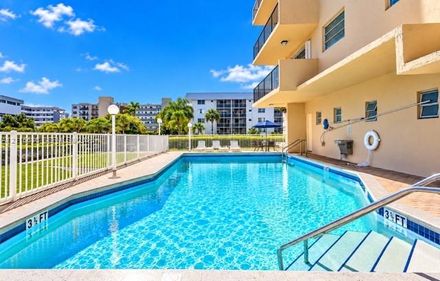 Swimming pool with integrated steps, tile border, surrounding perimeter fencing, and concrete decking