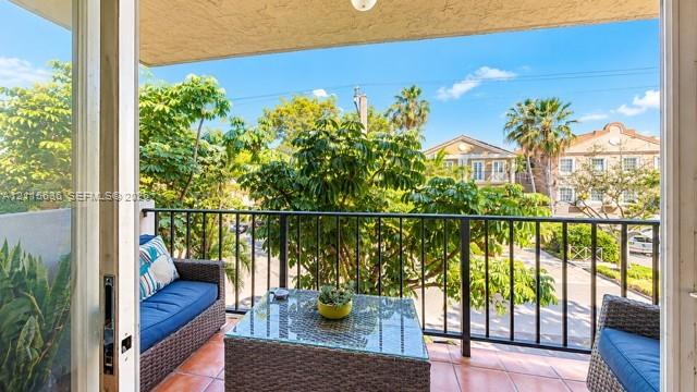 Covered balcony featuring tile flooring and a black metal railing