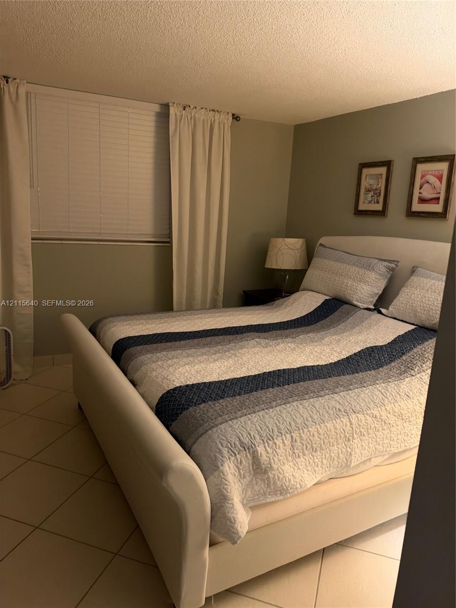 Neutral-toned interior walls, oversized ceramic floor tiling, and horizontal slat window blinds