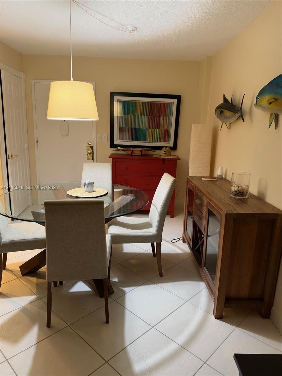 Light-toned tile flooring throughout with a suspended drum pendant light fixture and a multi-panel door