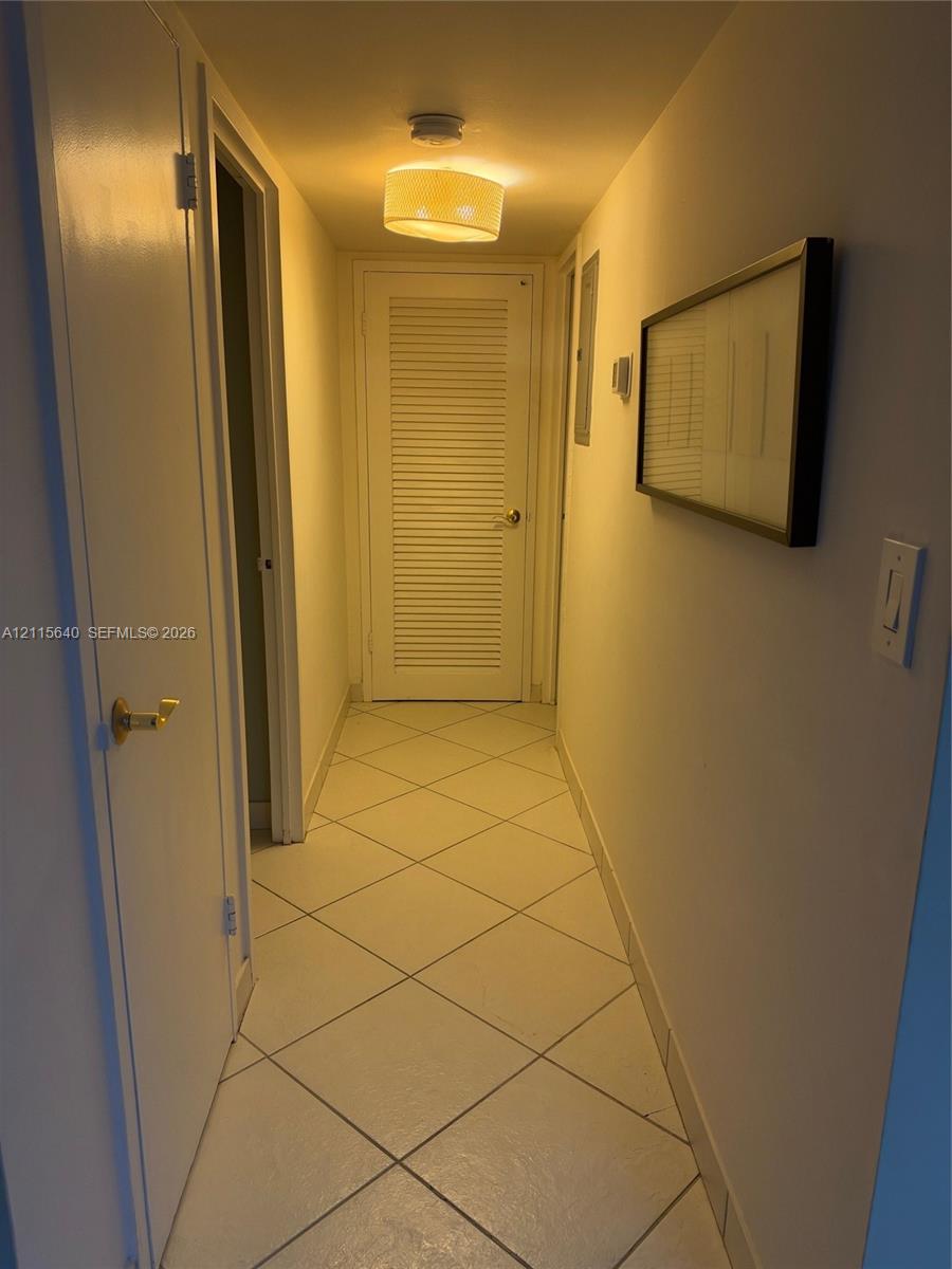 Hallway featuring diagonal-set tile flooring, a louvered door, and a drum-style ceiling light fixture