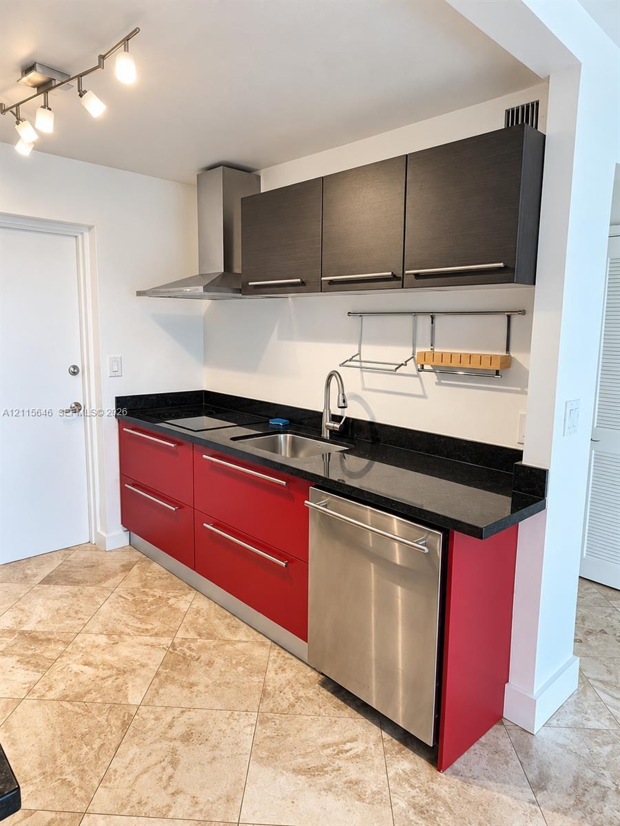 Kitchen featuring stone-finish countertops, stainless steel appliances, dark-toned upper cabinetry, vibrant base cabinetry, and track lighting