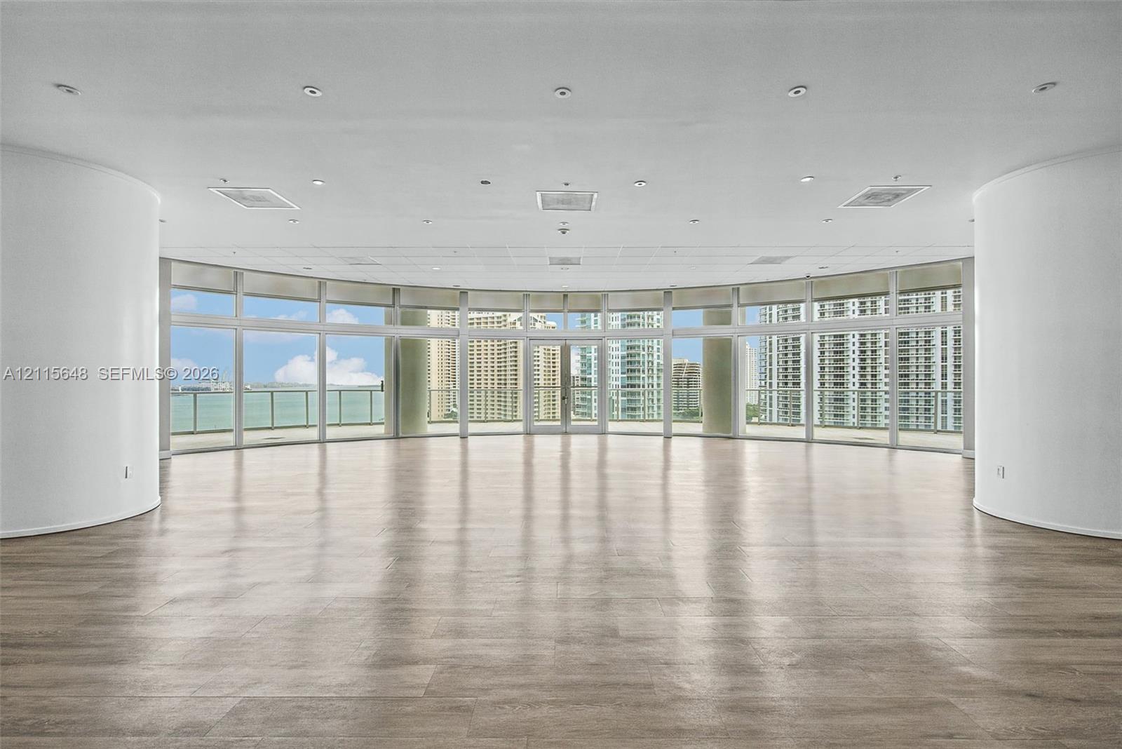 Curved interior wall architecture featuring floor-to-ceiling windows, wood-finish flooring, recessed lighting, and a wrap-around balcony